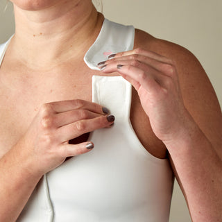 Front view of white Serena Bra for post-surgery recovery, showing close-up of adjustable strap being opened.