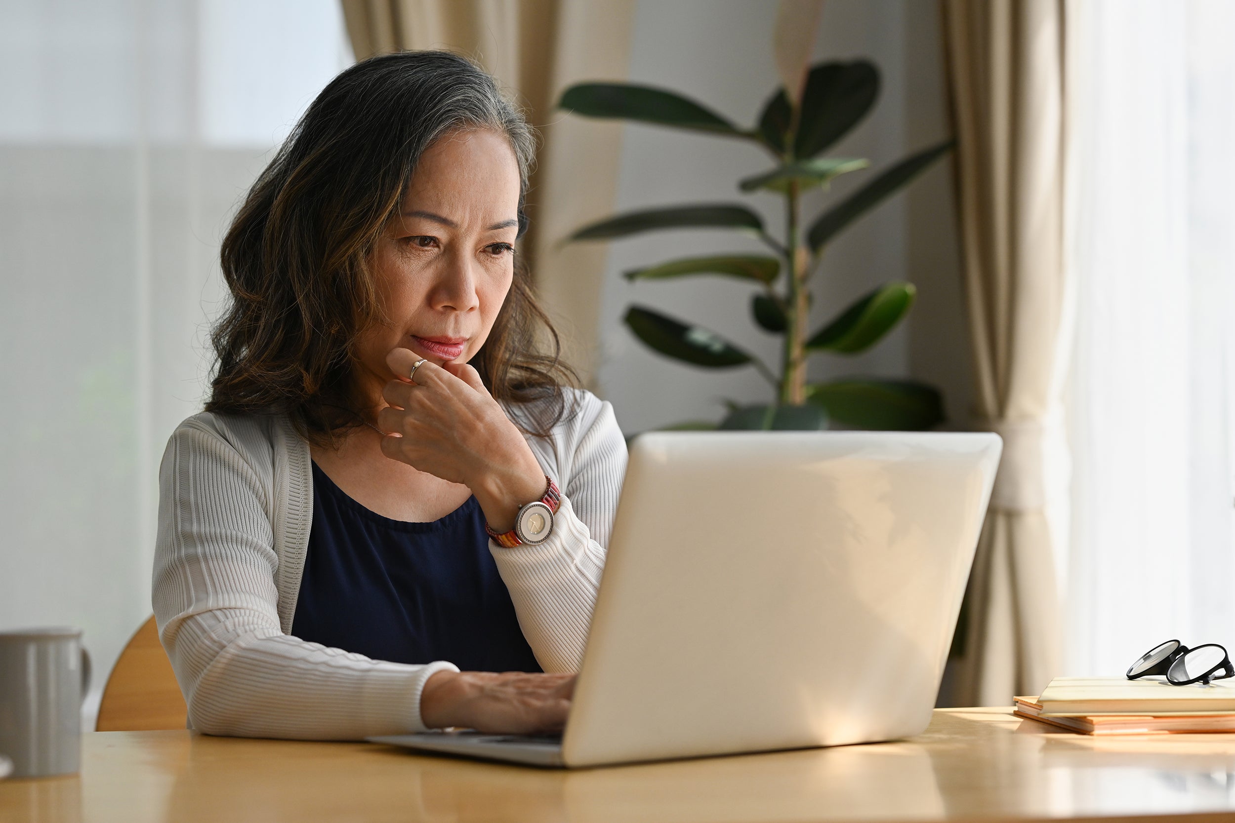A woman researches on her laptop. Yes, post-surgical bras are FSA and HSA eligible. Here's how to use that before your surgery date.