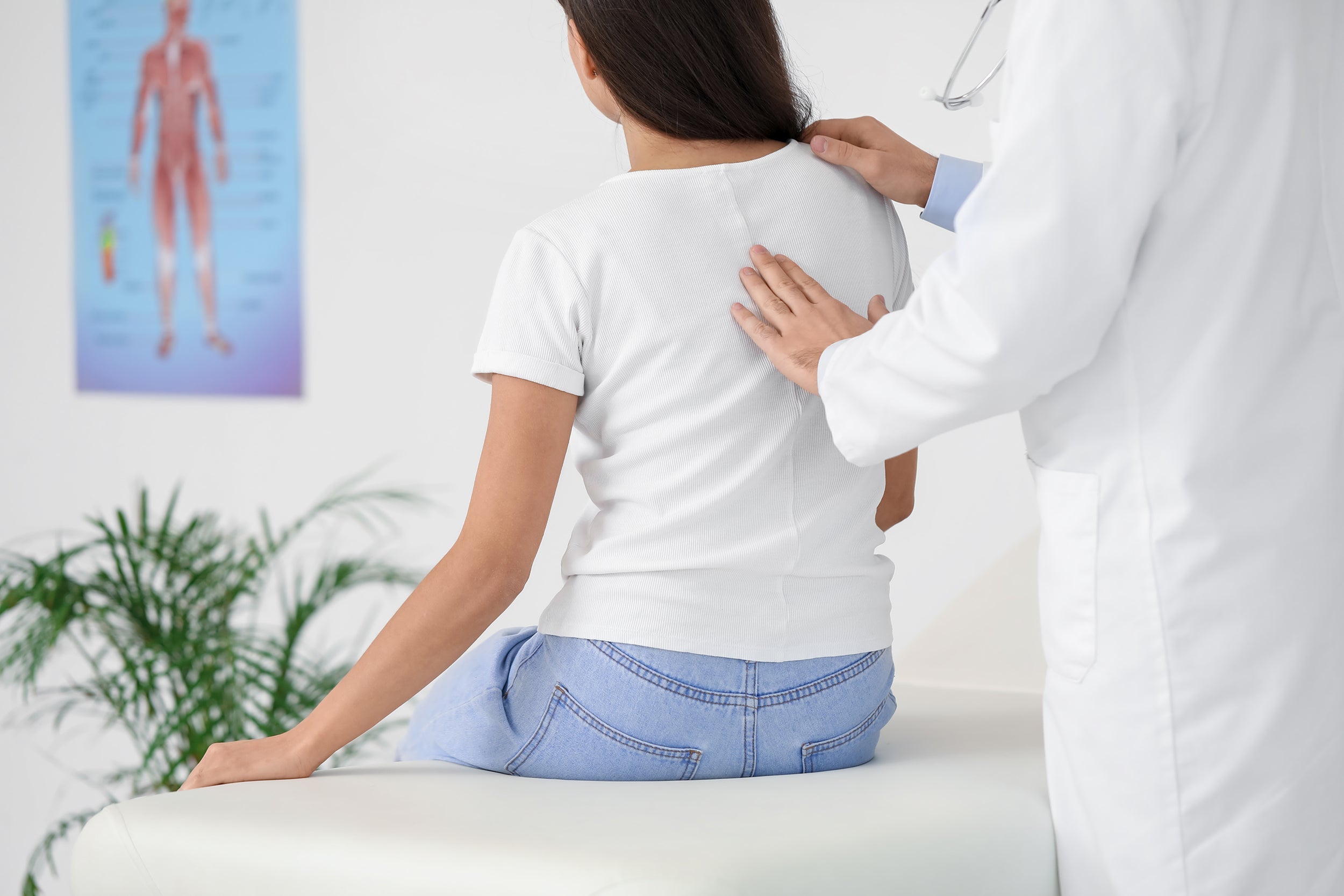 A woman has her spine evaluated by a doctor. If you've struggled to find a good bra with scoliosis, explore our complete guide on the best bras for scoliosis and get support today.