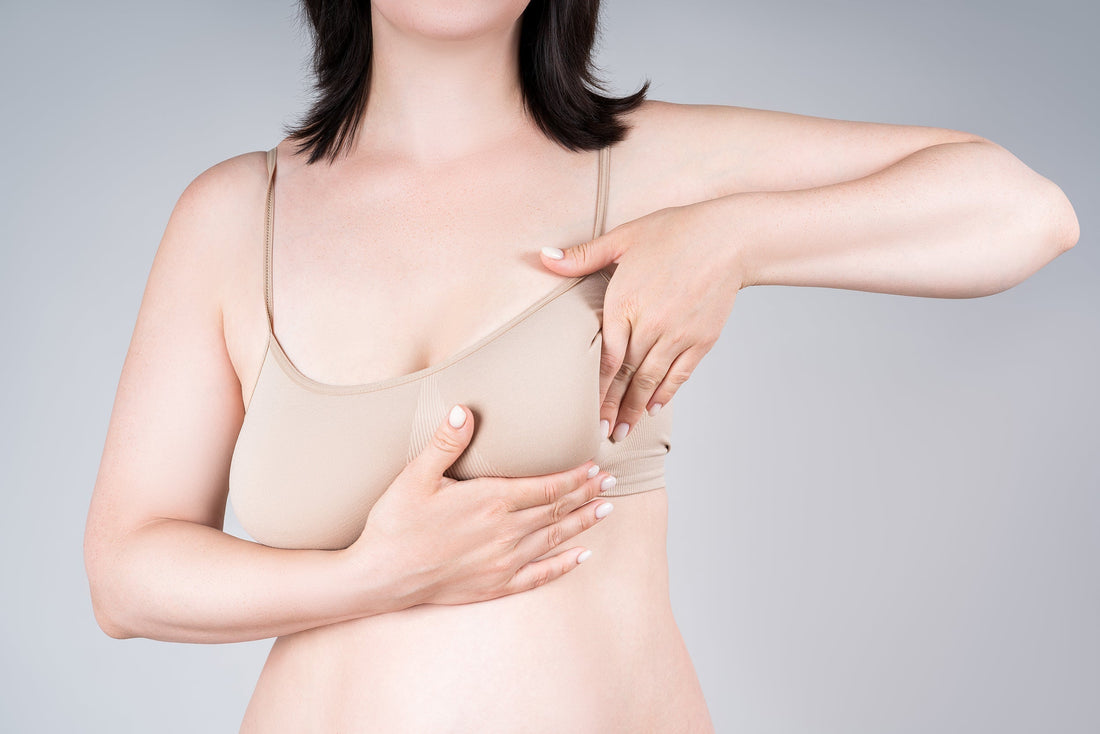 A woman looking at sagging breasts. Breasts change after weight loss—learn why, what helps, and how to prepare for surgery, including recovery bras that support healing from the very first day.