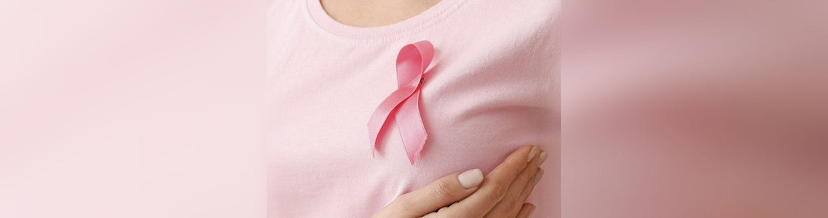 Chest of woman with pink shirt and pink ribbon holding breas