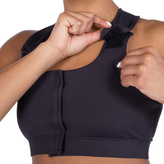 Front view of black Serena Bra for post-surgery recovery, showing adjustable strap being opened.