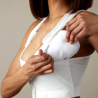 Front view of white Larissa Post-Surgical Bra for recovery with drain management, showing insert of puff into bra pocket.